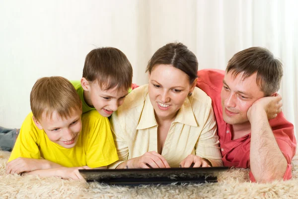 Family lying on the carpet with a laptop
