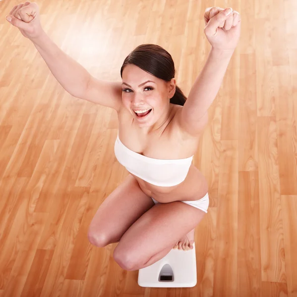 Happy girl on scales. Weight-loss.