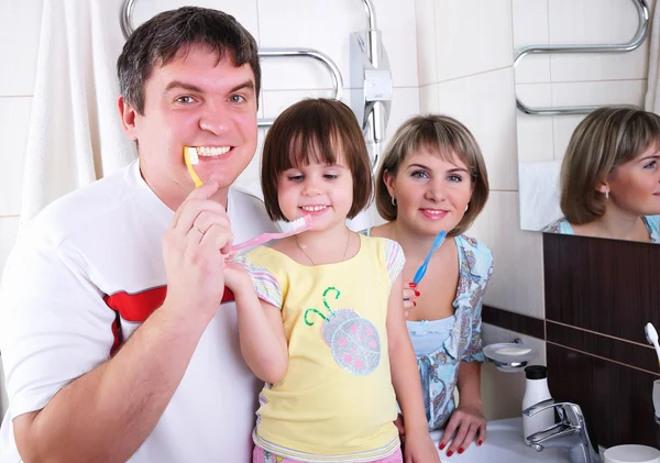 Mom, daughter and father brush their teeth