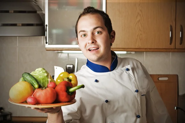 Happy man with vegetables on kitchen