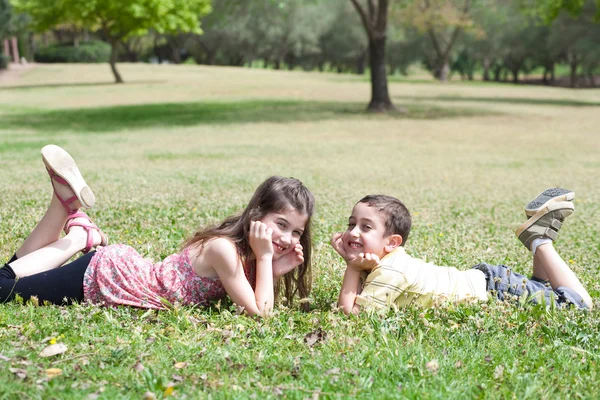 Cute children lie down on green grass