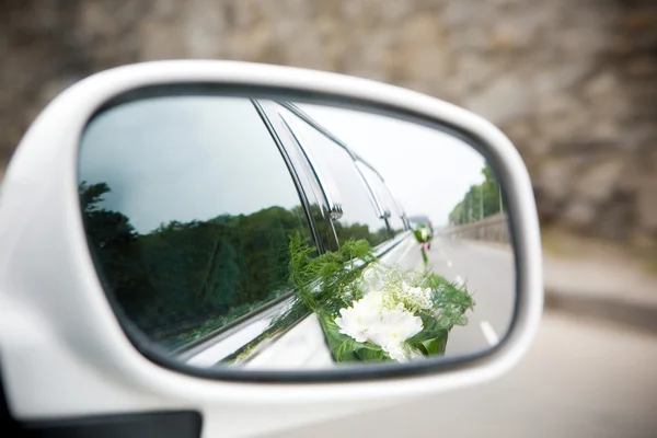 Landscape in the sideview mirror of a speeding wedding car