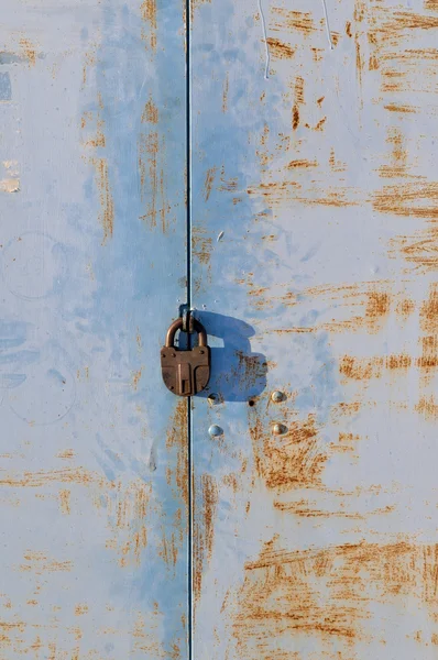 Rusty blue metal gate with padlock