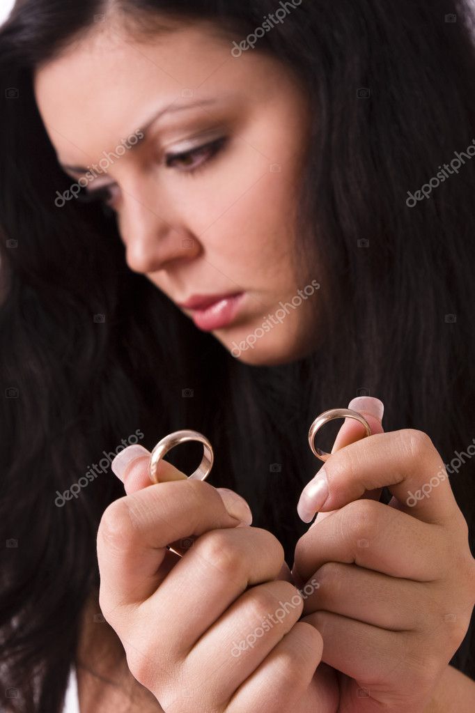 Distraught woman is very upset and holding gold wedding ring