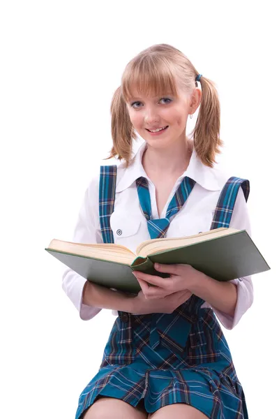 Schoolgirl is sitting on the stack of book and reading.