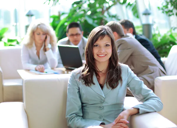 Business woman sitting in office with coworkers working in the background