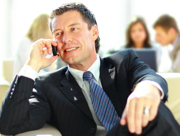 Concentrating businessman on call, coworkers talkling in background