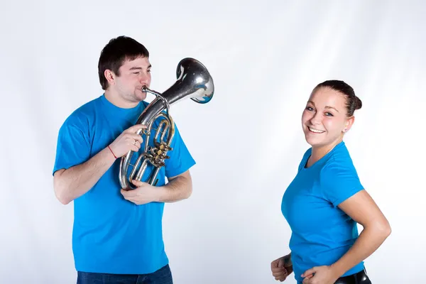 Man playing French horn woman is dancing