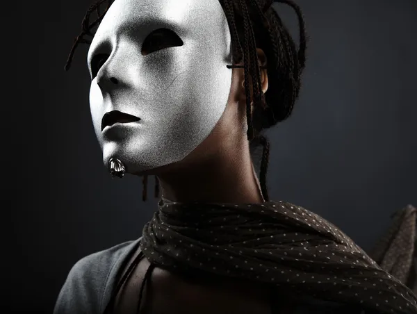 Gloomy woman in silver mask posing on a black background.