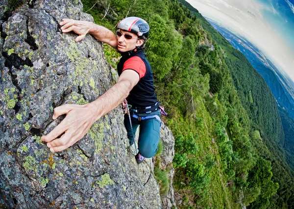 Young white man climbing a steep wall