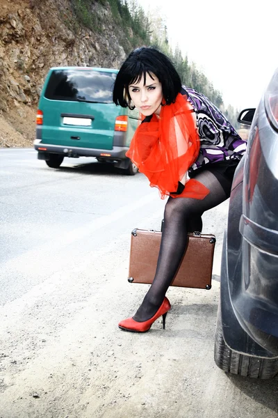 Sexy woman with baggage near to car