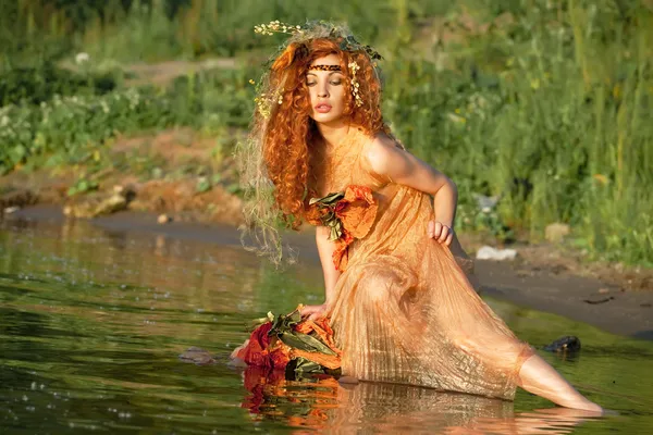 Red-haired woman sitting in water.