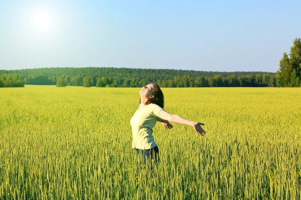 Woman with open arms in the green cereal field.