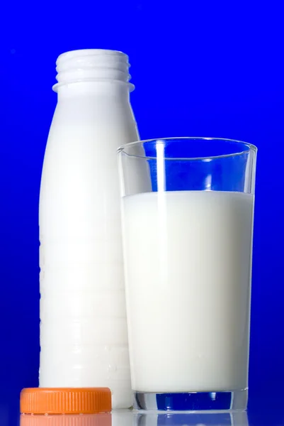 Milk in glass and open bottle isolated on blue