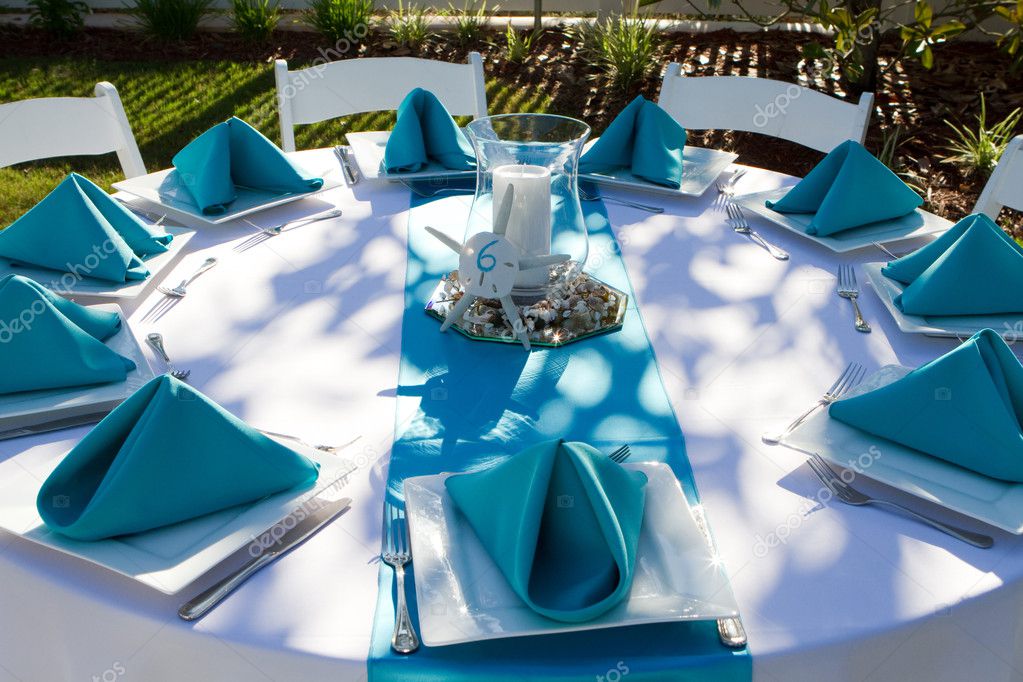 Outdoor dinner table is setup with plate silverware and folded napkins for 