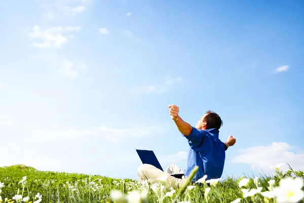 Freedom - Man working with laptop in a meadow of flowers with copyspace