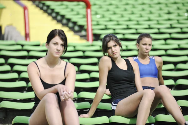 Group of athletics girls relax at soccer stadium