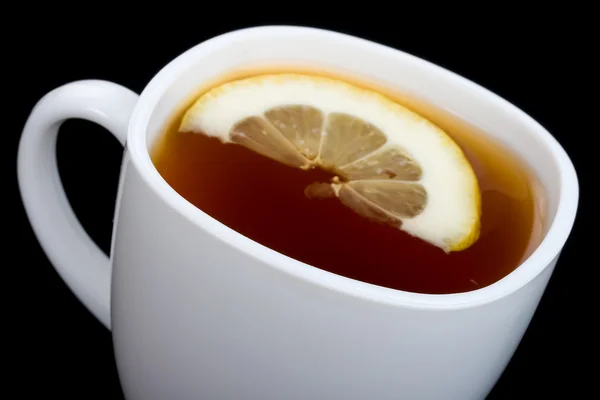 Close-up cup of tea with lemon on black