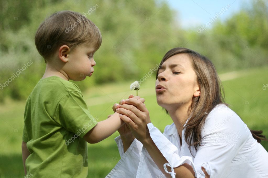 child blowing dandelion