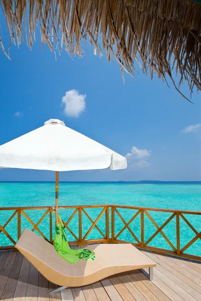 Parasol and chaise lounge on a terrace of water villa, Maldives