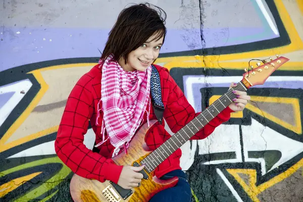closeup portrait of a happy young girl with guitar and graffiti
