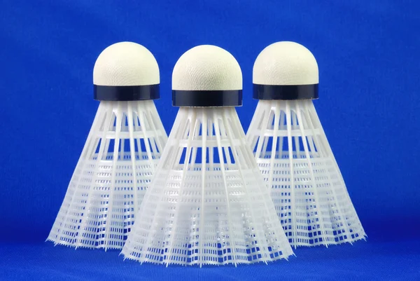 Three badminton shuttlecocks isolated on blue concepts of sports