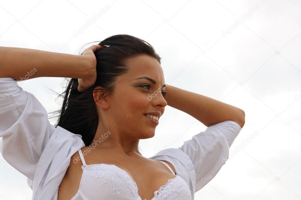Beautiful tanned girl in white against the sky