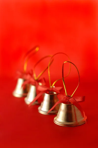 Four golden christmas bells with red bac