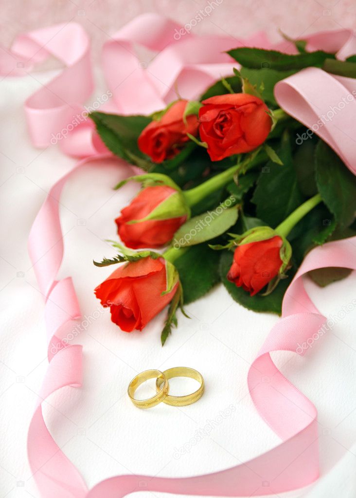 Red roses and wedding rings with decoration of pink ribbon