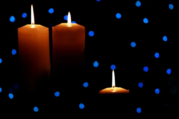 Three large candles amongst blue lights