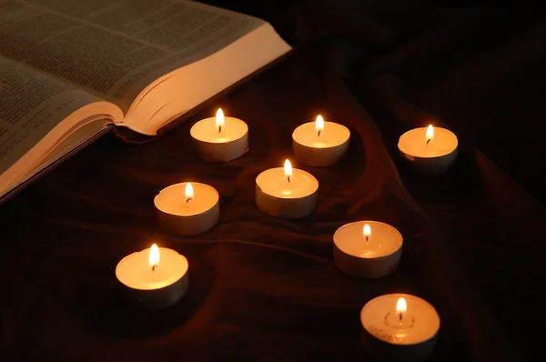 Arrow of candles pointing at Bible