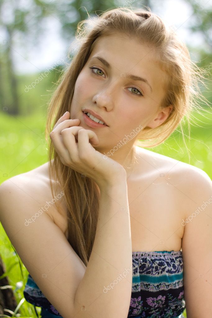 Portrait of beautiful teen girl with hand near the face in the park