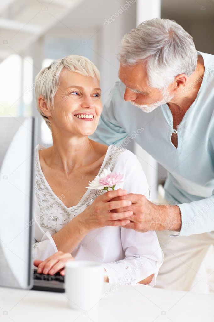  - depositphotos_3326593-Old-man-giving-flower-to-wife-while-shes-working-on-computer