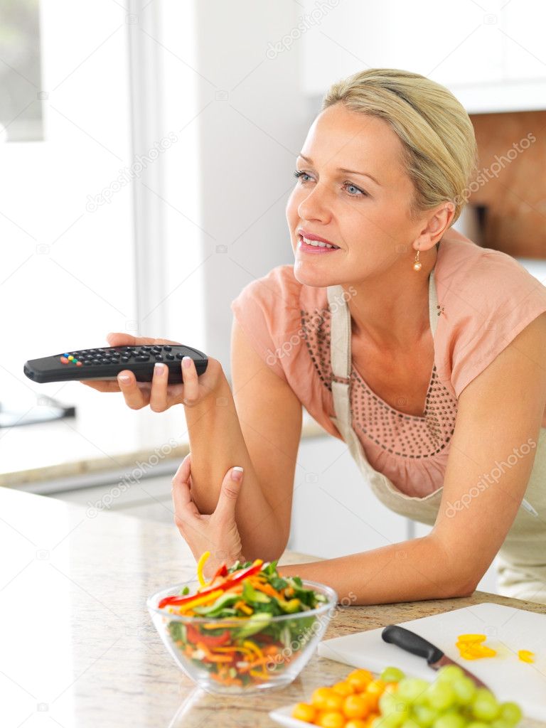 Beautiful mature in the kitchen watching television while preparing salad depositphotos 3339243 Middle aged woman with the TV remote while preparing dinner in t Beautiful mature in the kitchen watching television while preparing salad