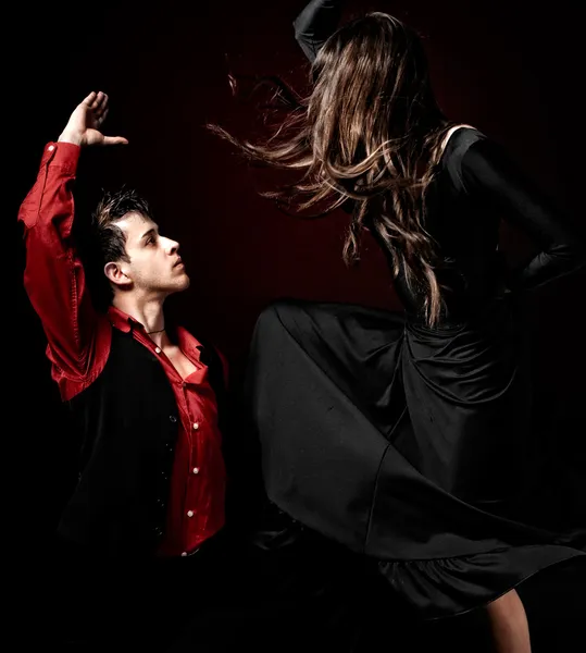 Young couple passion flamenco dancing on red lig
