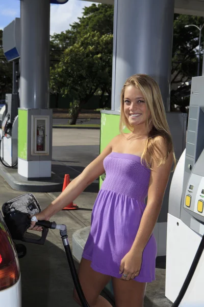 Beautiful teenage girl putting gas into her car