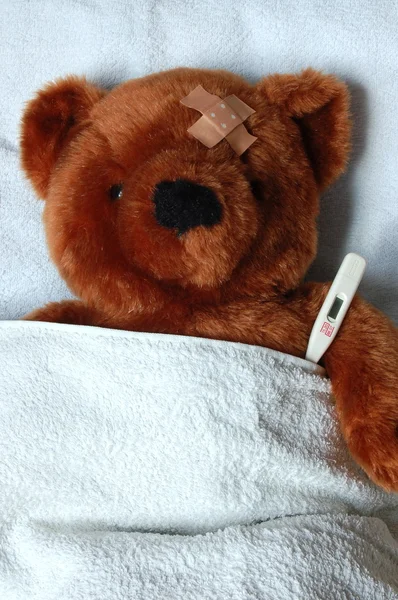 Sick teddy with injury in bed