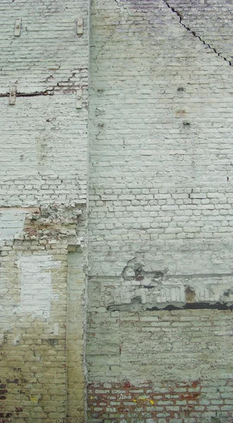 Large worn white industrial brick wall with crack and damage