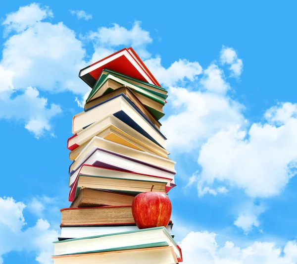 Pile of books and apple against blue sky