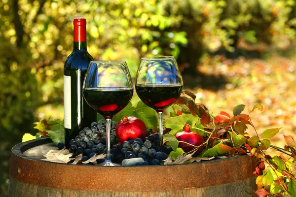 Glasses of red wine on old barrel with autumn leaves