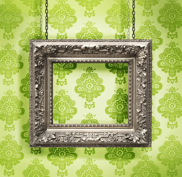 Silver picture frame hung against floral wallpaper background