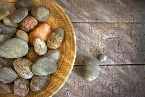 Spa rocks in wooden bowl on rustic wood