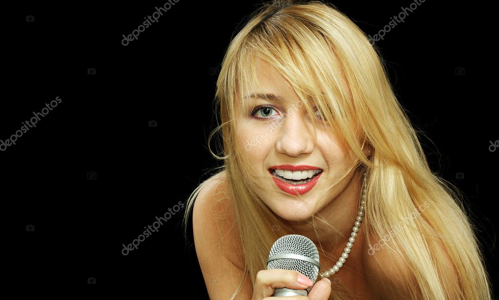 Portrait of blonde girl with naked shoulders singing in microphone