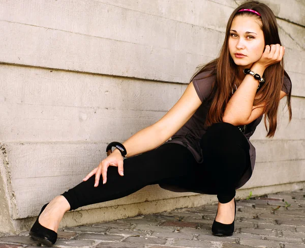 Sepia portrait of the girl squatting by the concrete wall by Oleksandr Pekur 