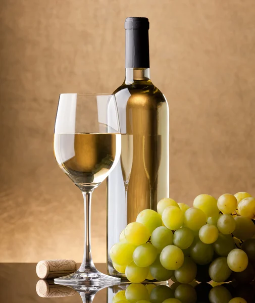 A bottle of white wine, glass and grapes
