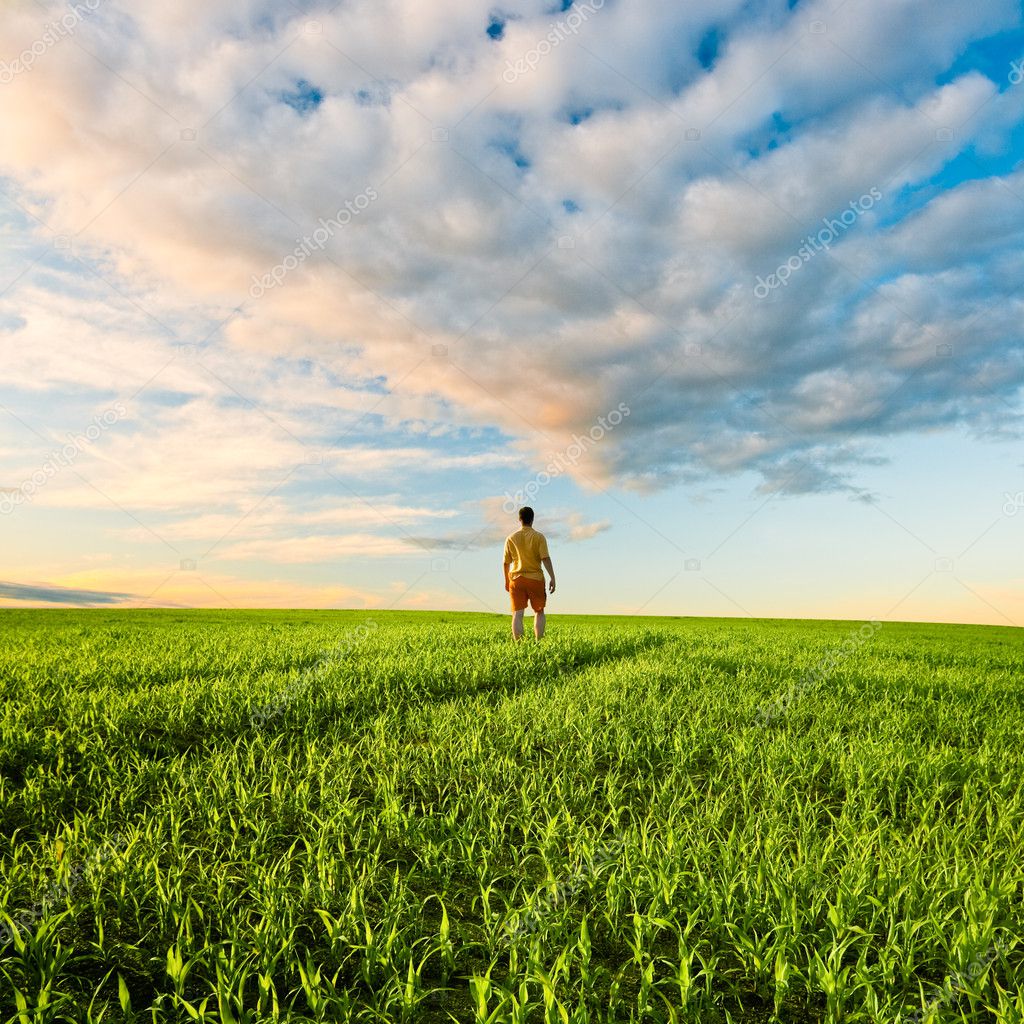 Man on green field under sunset skies — Stock Photo 3482878