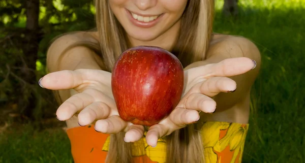 A girl shows a red apple