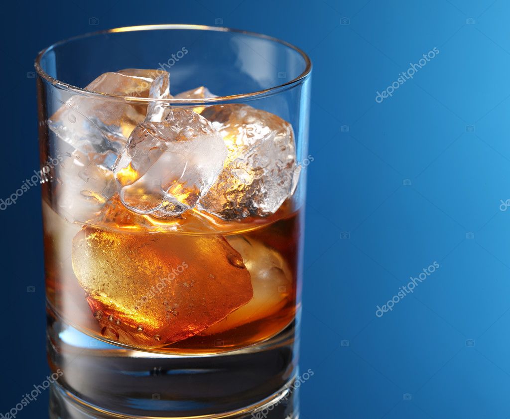 Glass of brandy with ice cubes isolated on a blue — Stock Photo