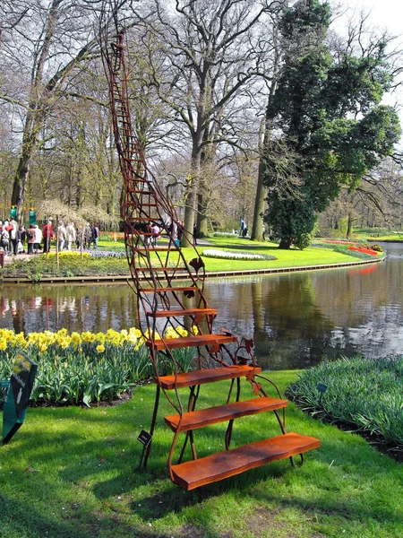 A sculpture in a botanical garden on the bank of lake, a ladder in the sky