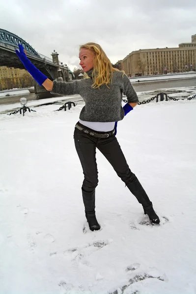 The girl dances about the bridge in the winter on snow